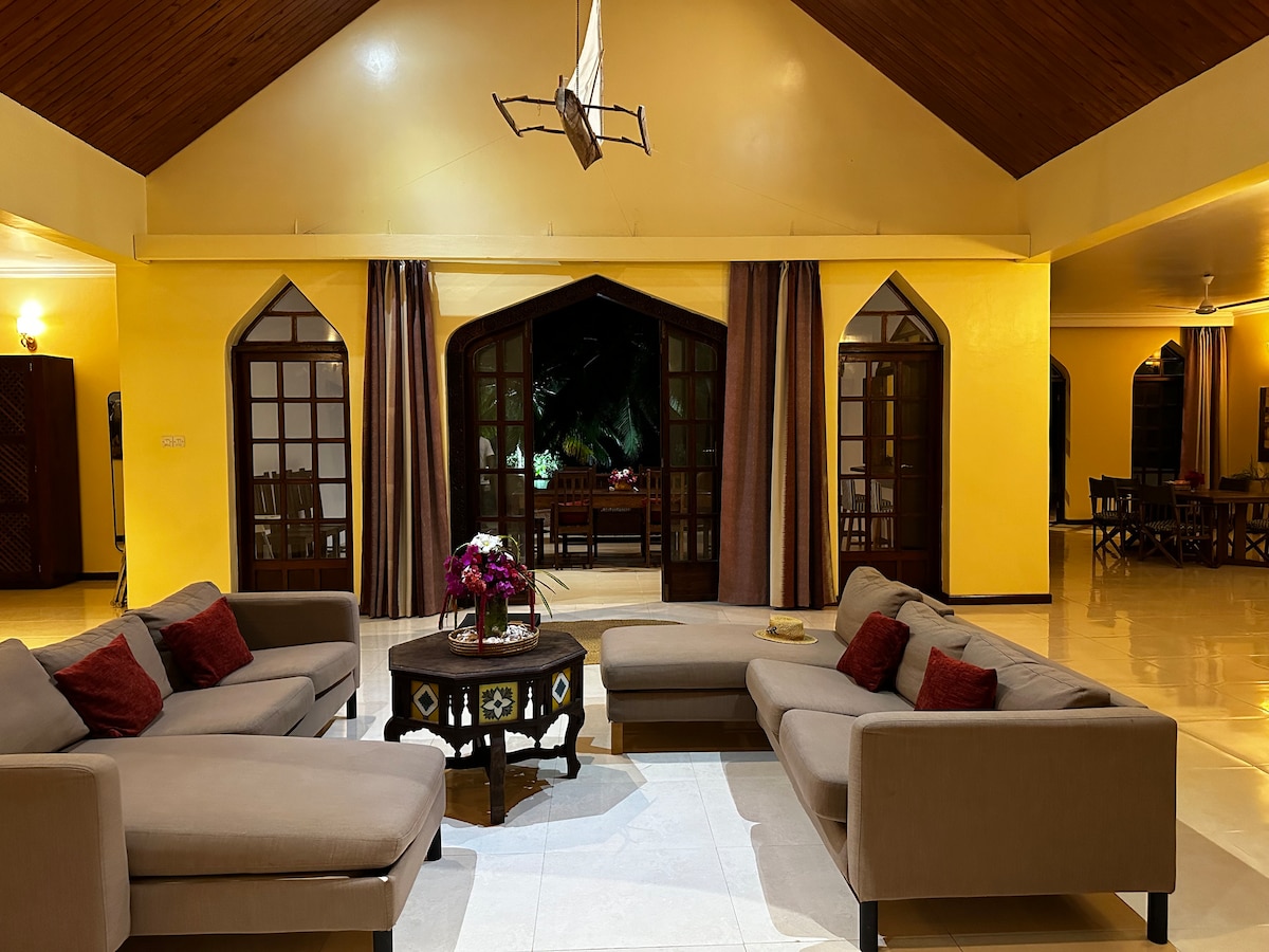 Living room with L-shaped sofas, vaulted wood ceiling and model dhow overhead